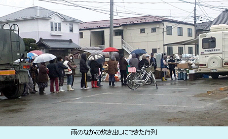 雨のなかの炊き出しにできた行列