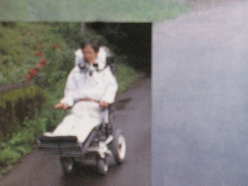 白の散歩服を着て電動車椅子を動かす星野さん（筆者撮影）
